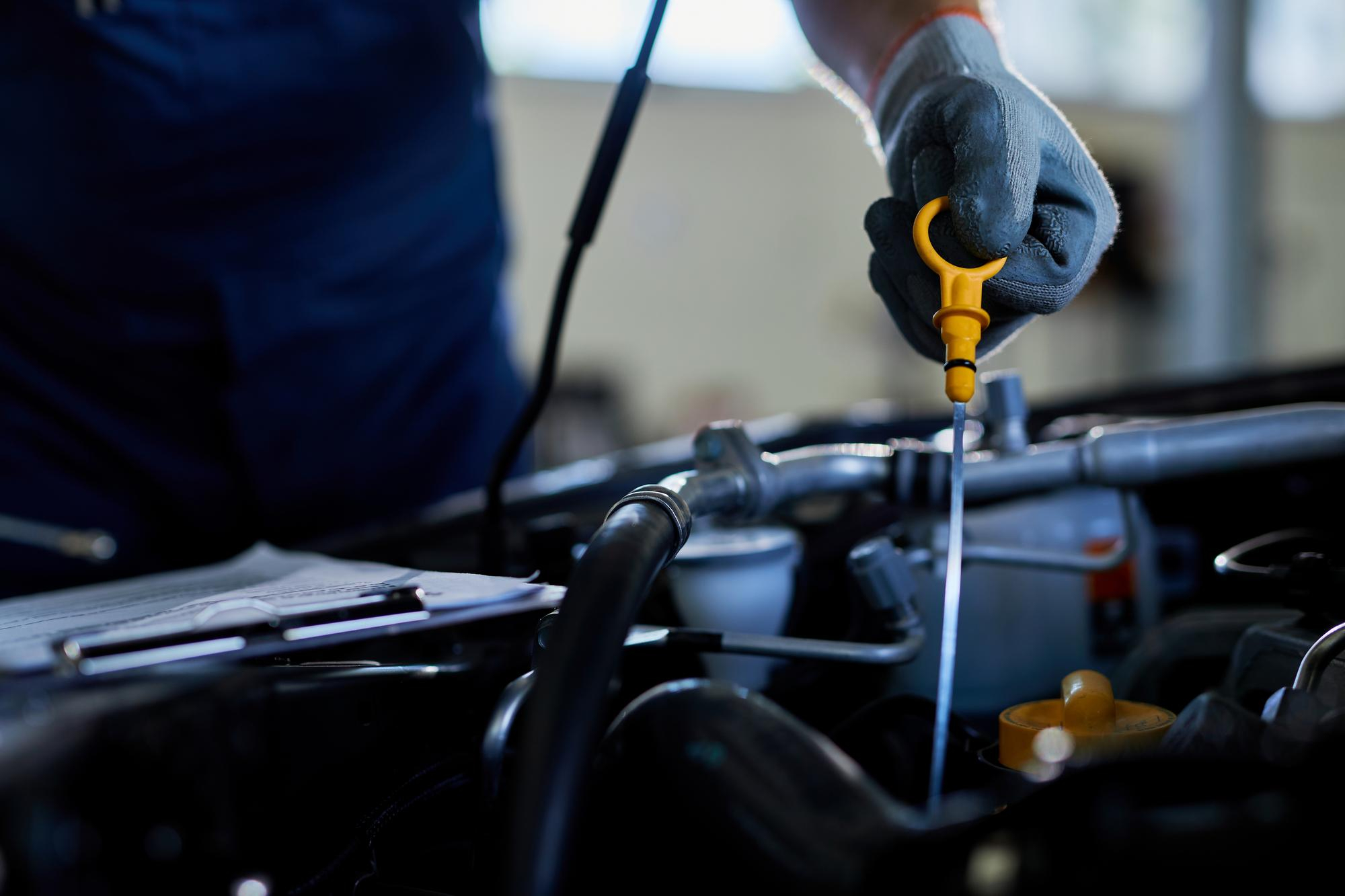 Mechanic checking engine oil level using a dipstick